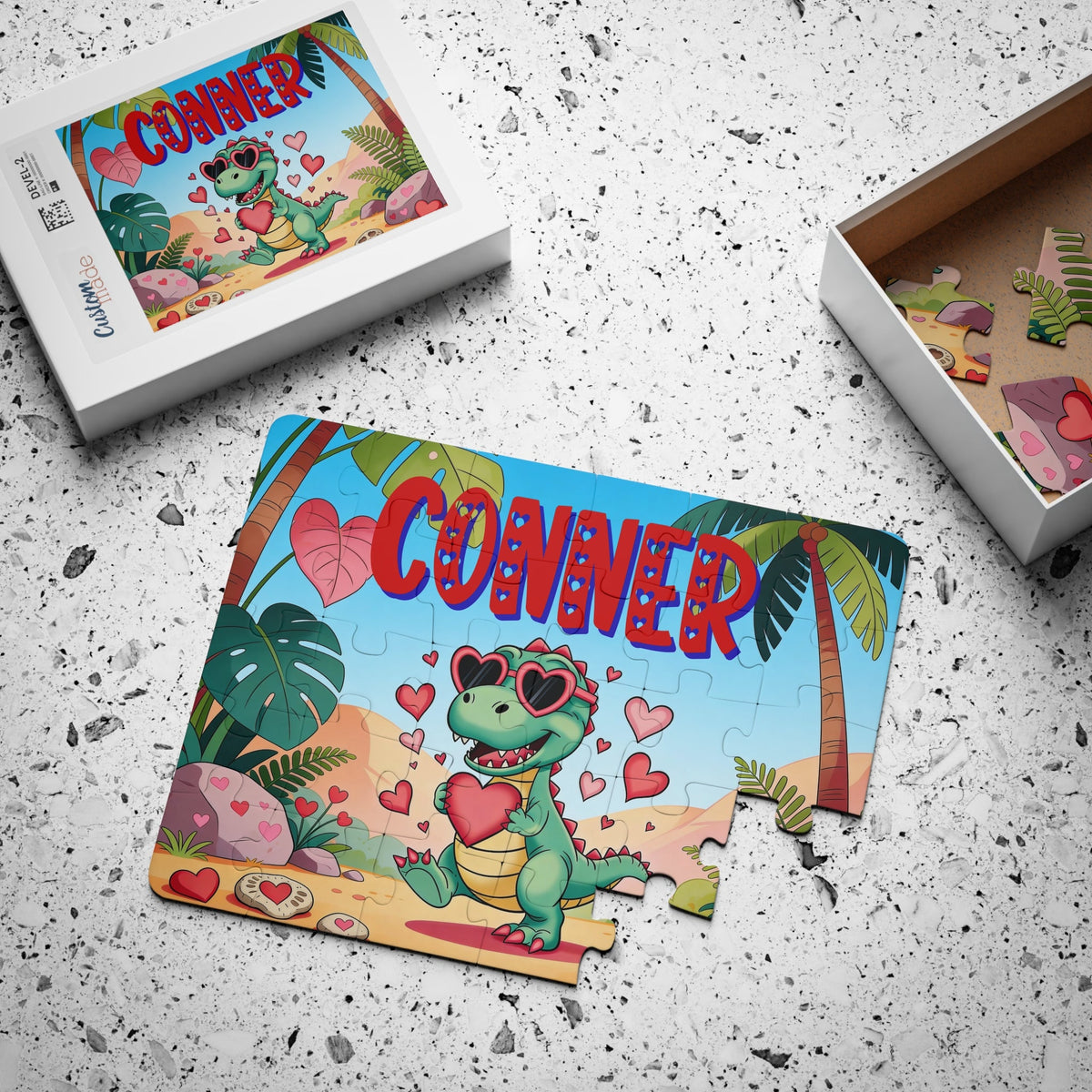 Personalized children’s jigsaw puzzle displayed with the matching puzzle box and loose pieces. The colorful dinosaur design features a customizable name printed prominently across the top of the puzzle image.