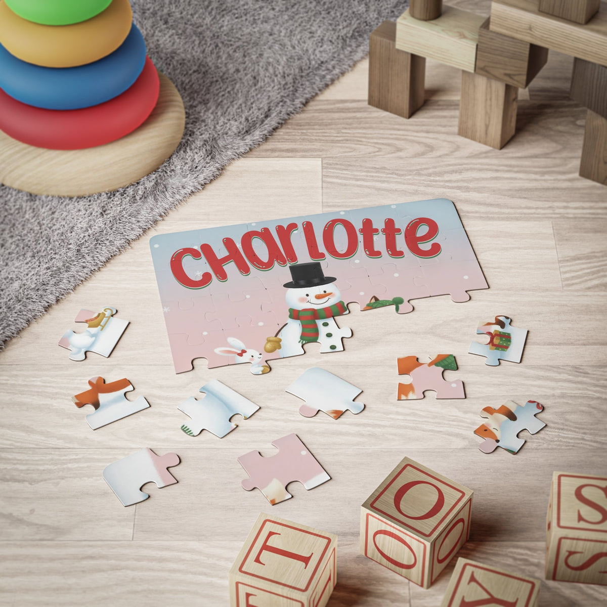 Custom name kids jigsaw puzzle shown partially assembled on the floor during playtime, featuring a winter snowman and animal friends design with the personalized name displayed at the top.