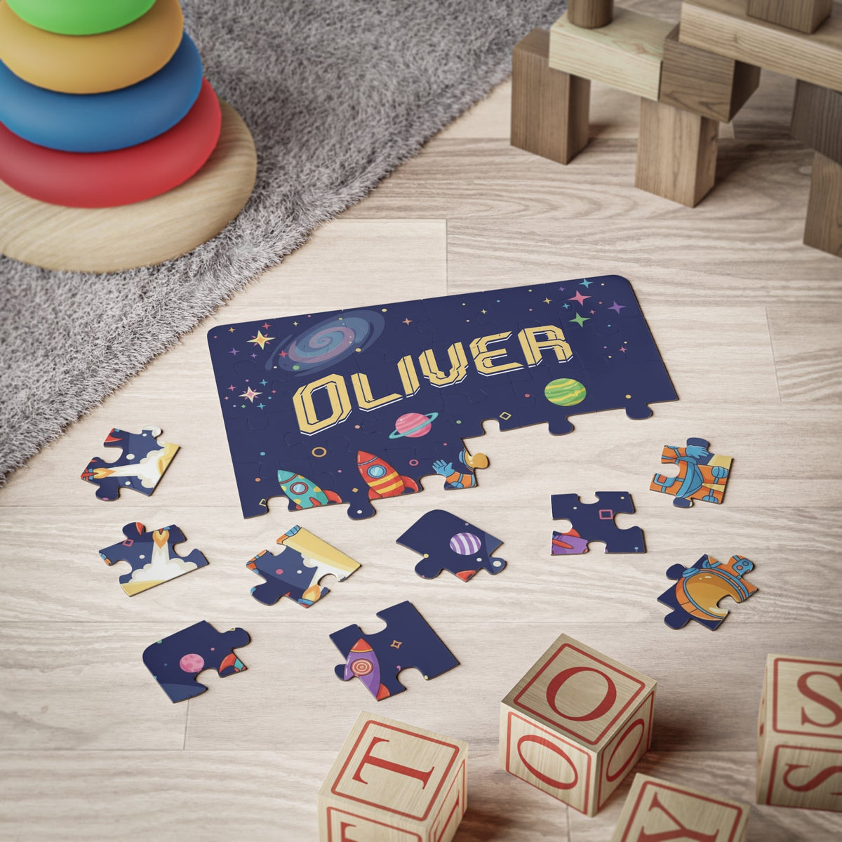 Personalized astronaut name puzzle for kids shown on the floor with scattered pieces, colorful rockets, planets, and a playful outer space design.