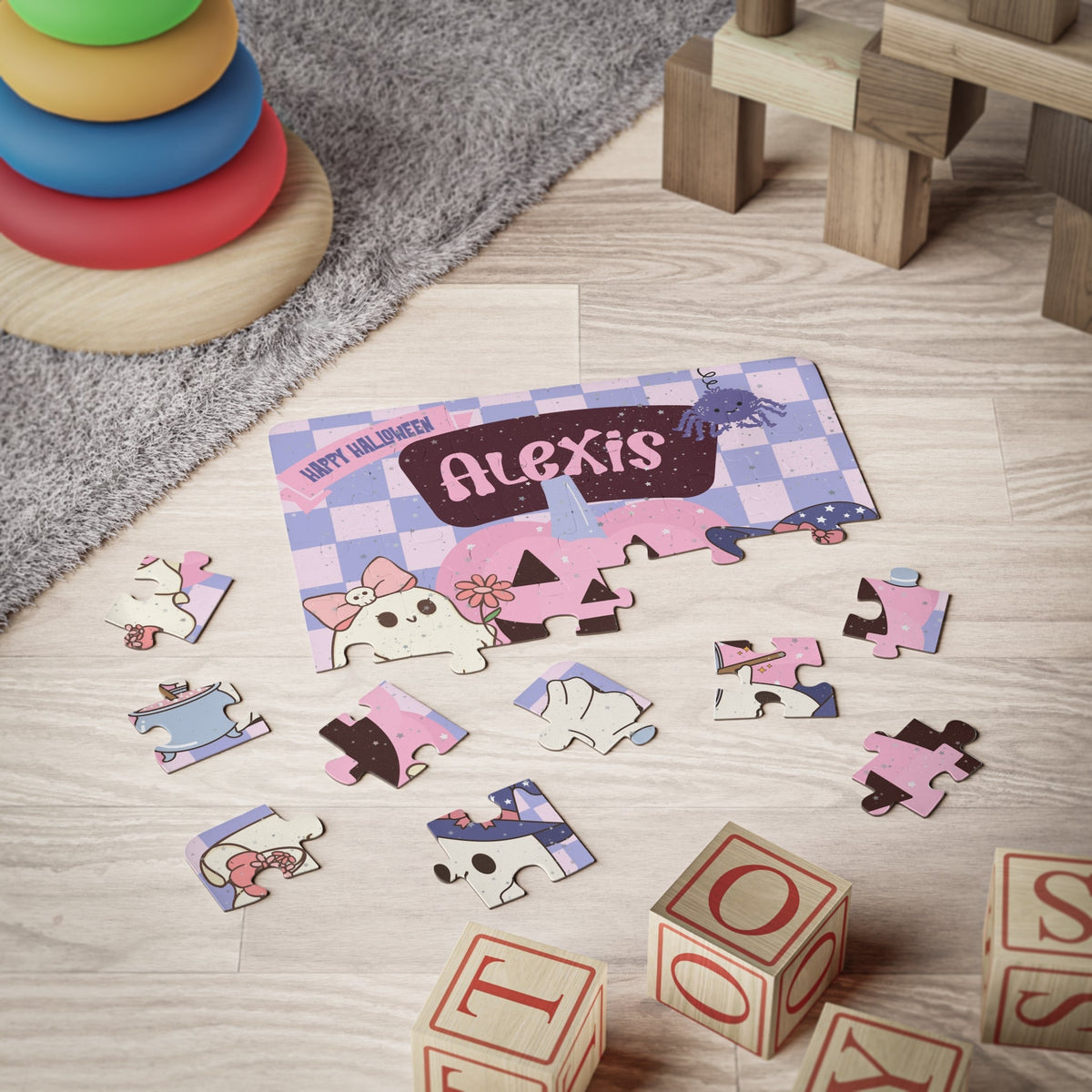 Personalized Halloween kids jigsaw puzzle with a customizable child’s name displayed across the top of the design, shown partially assembled with cute ghost and pumpkin characters in a playroom setting.