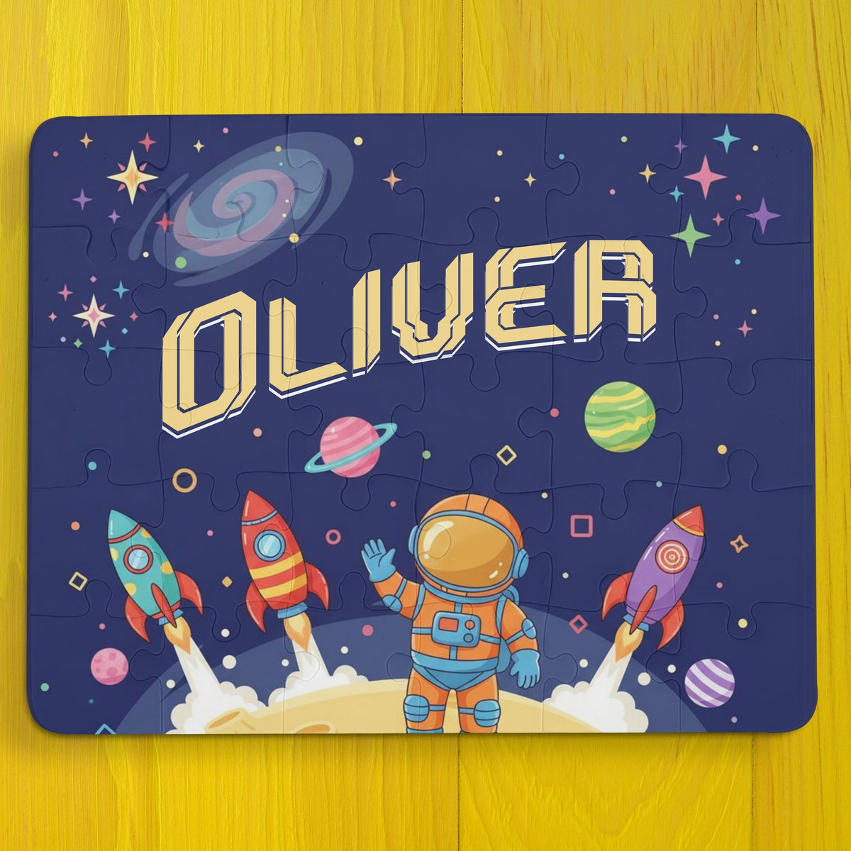 Personalized space-themed kids puzzle featuring a cartoon astronaut, rockets, planets, and stars, with the child’s name displayed across the top in bold lettering.