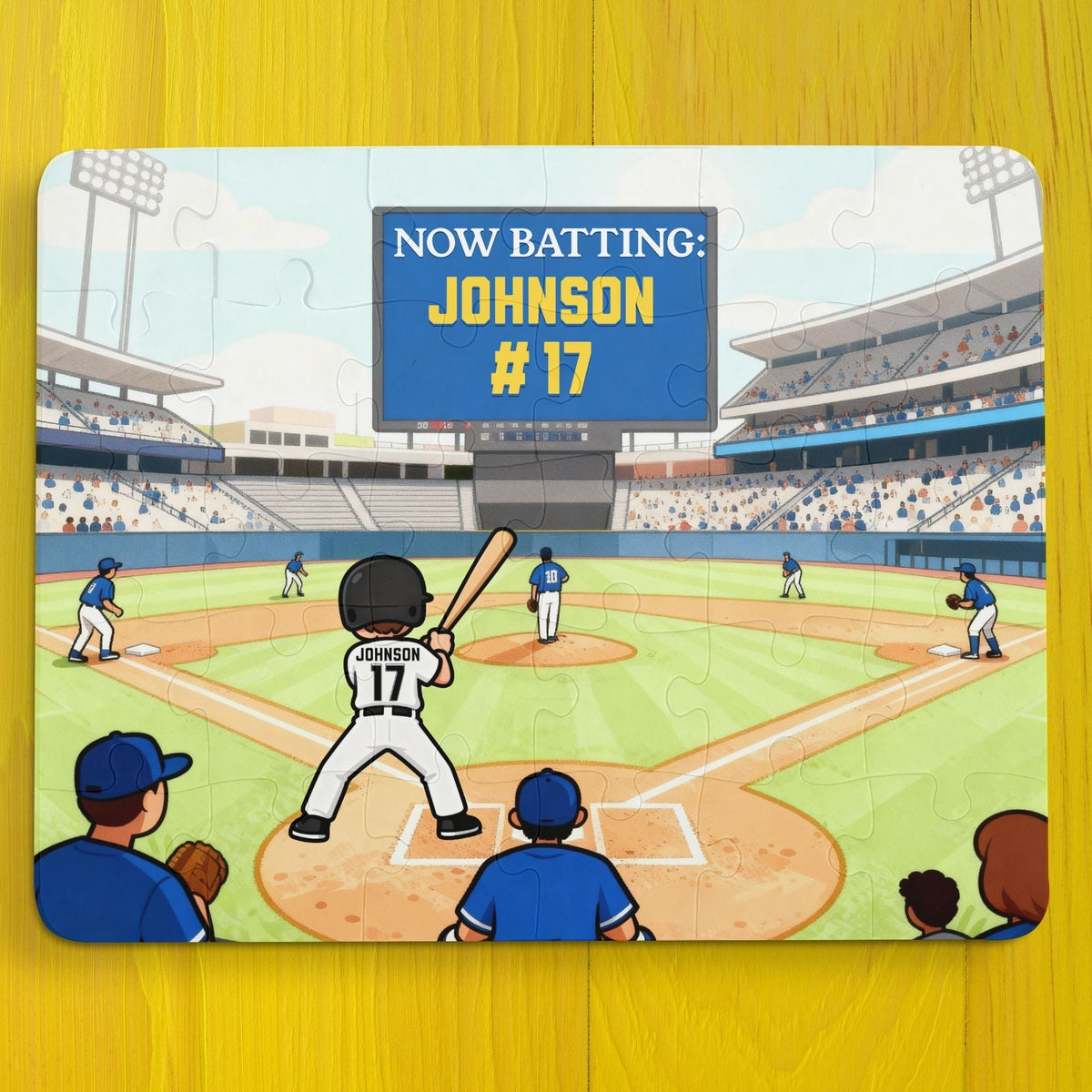 Personalized baseball puzzle showing a child standing at home plate in a packed stadium, holding a bat, with a digital scoreboard that reads “Now Batting: Johnson #17.” The player’s name and jersey number can be customized, and the colorful illustrated field includes teammates, fans, and stadium lights.