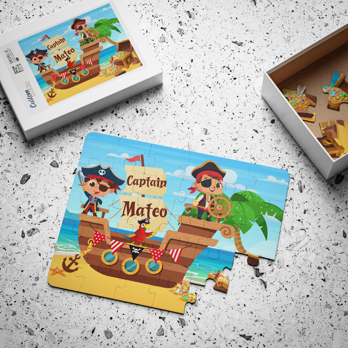 Personalized pirate-themed jigsaw puzzle for kids with matching keepsake box. The custom name selected by the customer appears printed on the puzzle and on the box label. Image shows the completed puzzle next to the open box with jigsaw pieces inside.