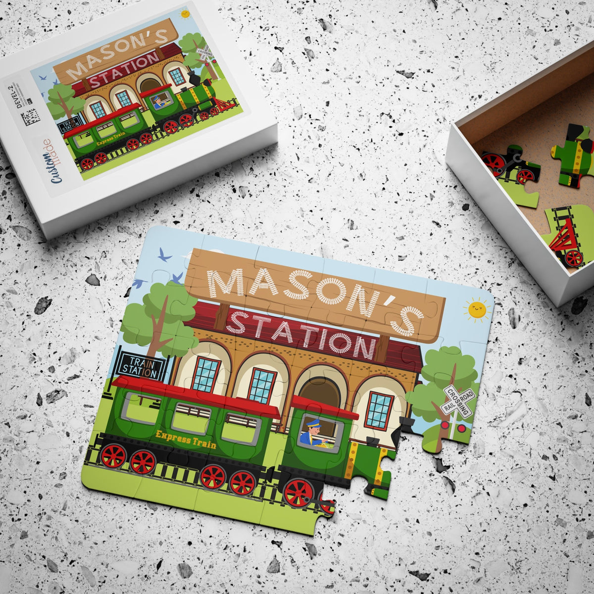 Personalized kids train station jigsaw puzzle displayed with its box, featuring a train scene and a customizable name printed prominently at the top of the puzzle.