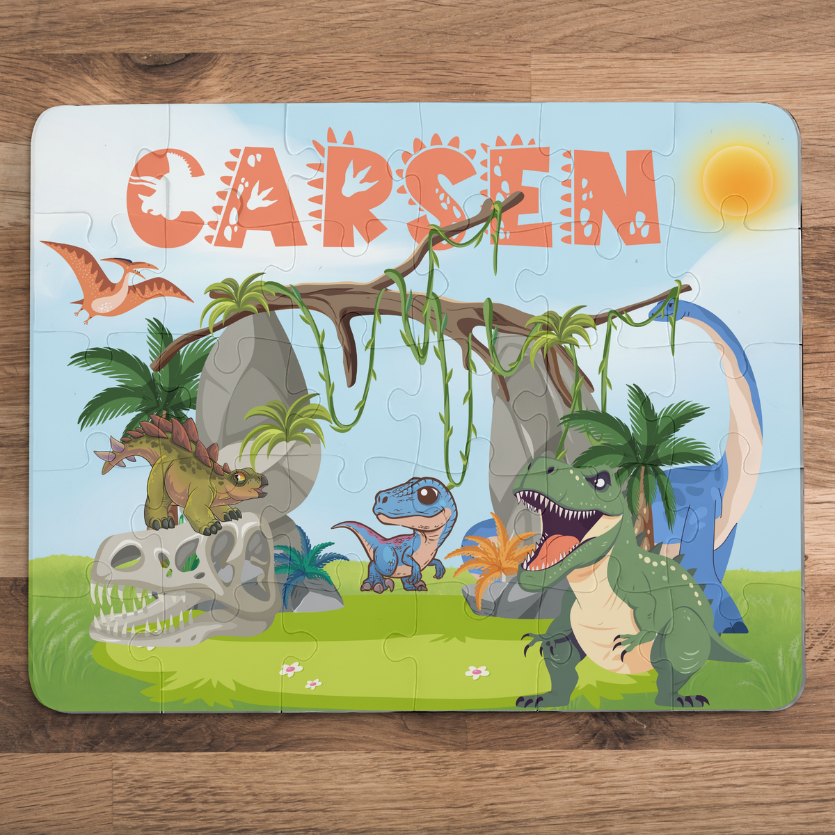 Personalized dinosaur name puzzle for kids featuring a colorful Jurassic scene with multiple cartoon dinosaurs, vines, rocks, and palm trees. The child’s name is customizable and appears large across the top of the puzzle (shown as “Carsen”), making this a custom 30-piece jigsaw designed for toddlers and young children.