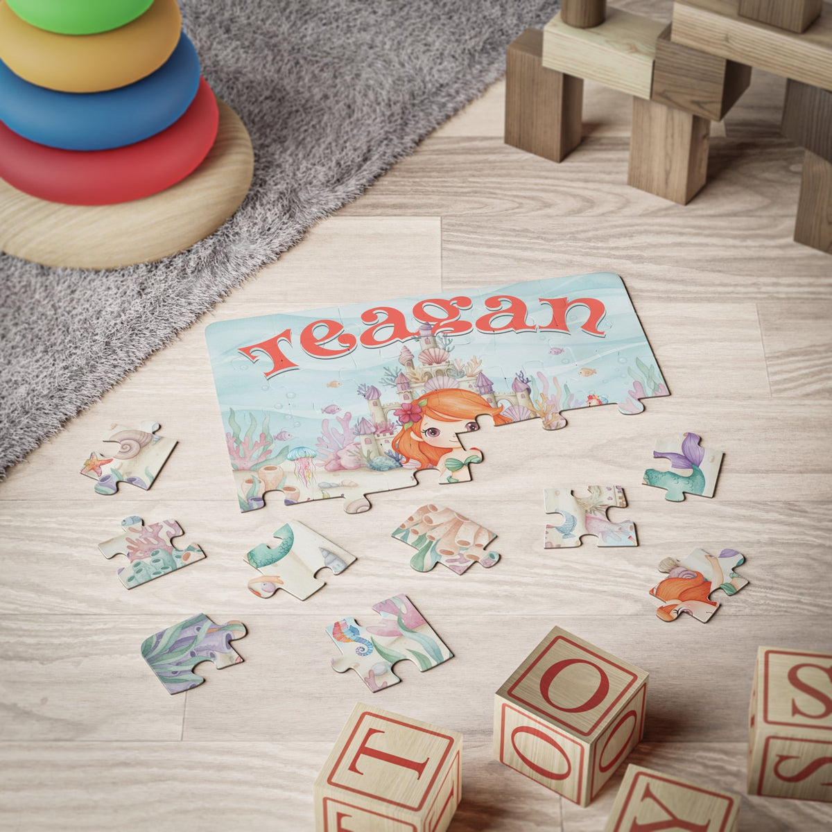 30-piece personalized mermaid name puzzle shown on a playroom floor with scattered pieces, designed for toddlers and young children learning through play