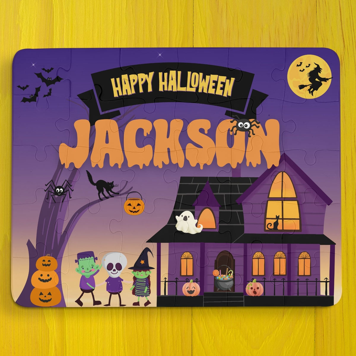 Personalized Halloween kids puzzle featuring a spooky haunted house scene with trick-or-treaters, pumpkins, bats, and a purple night sky. The puzzle includes a customizable child’s name displayed across the top and is a 30-piece jigsaw designed for young children.