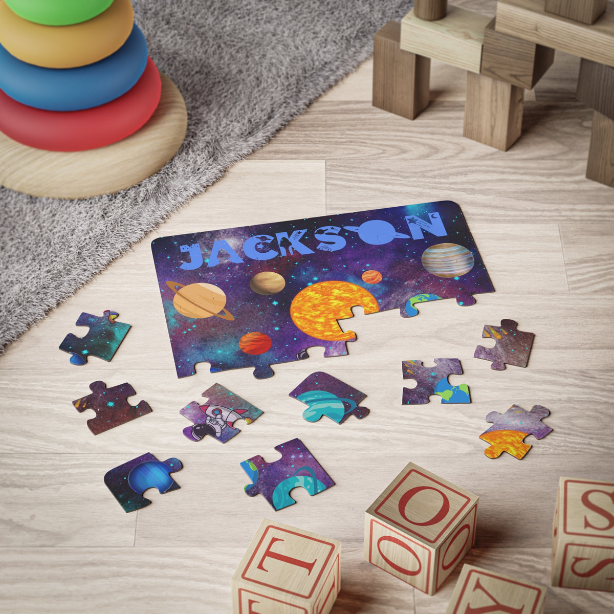 Personalized space-themed puzzle for kids shown partially assembled on the floor with loose puzzle pieces, displaying planets, stars, and the child’s custom name across the top. Educational toy for learning about the solar system.