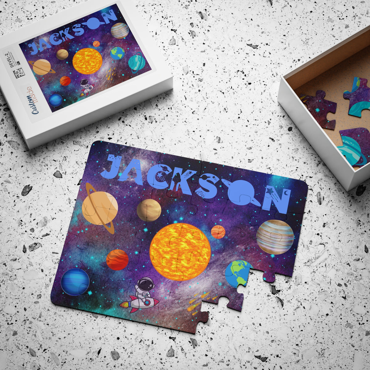 Custom name solar system puzzle for children displayed with its box and loose pieces, showing bright planets, outer space background, and the personalized name across the top. Fun educational jigsaw puzzle for kids.