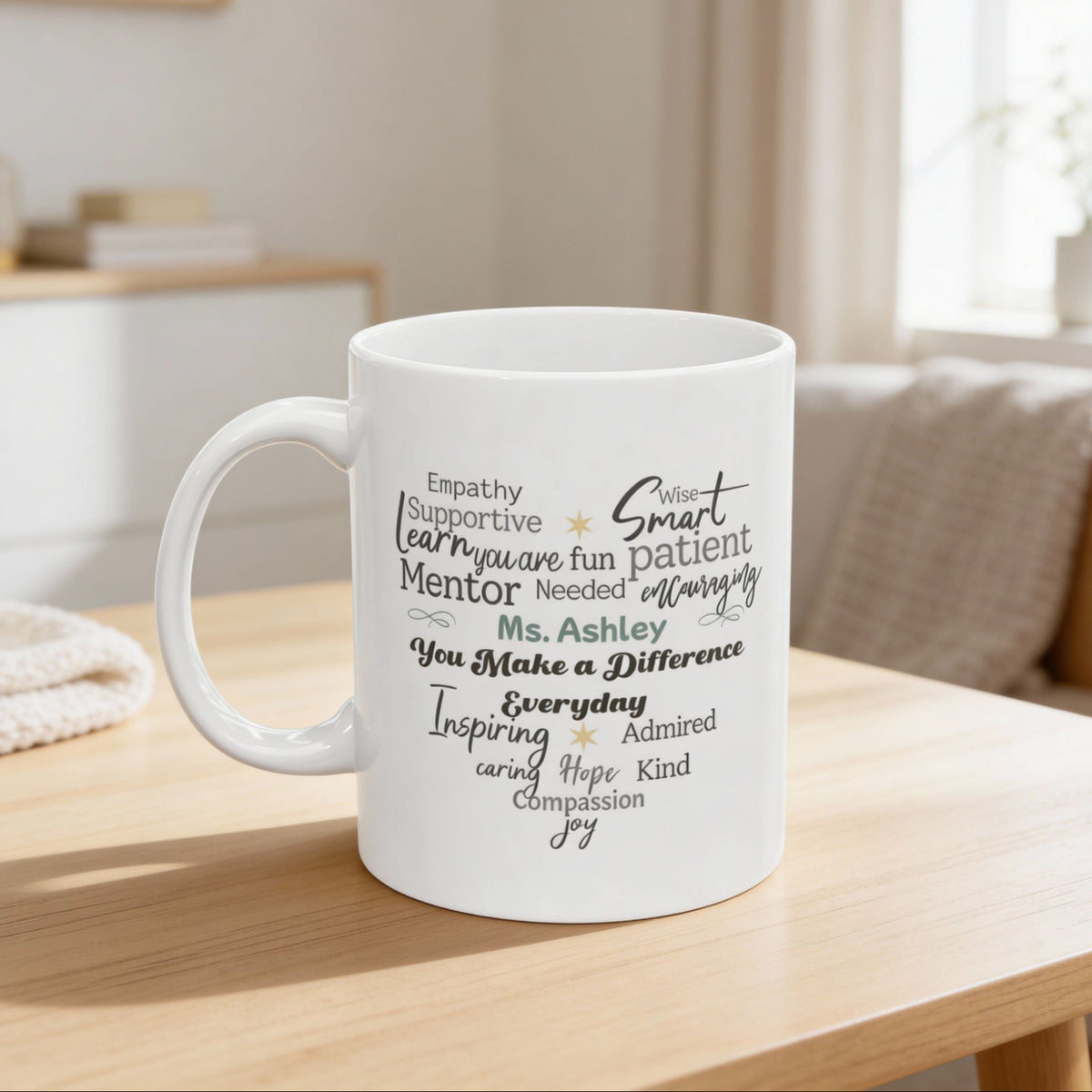 White ceramic mug featuring a heart-shaped word cloud design with positive traits and a customizable name displayed in the center of the heart. Personalized text appears on the front of the mug. Shown in a bright, neutral home setting on a wooden table. Available in 11oz and 15oz sizes.