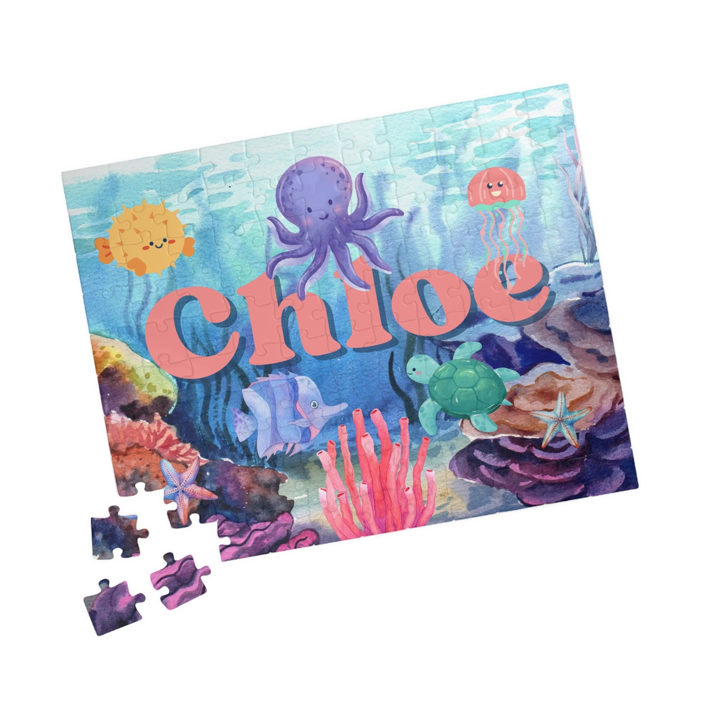 Personalized ocean 110-piece jigsaw puzzle shown at an angle with a few loose jigsaw pieces nearby. The underwater illustration includes sea creatures and coral, with a custom name integrated into the artwork.