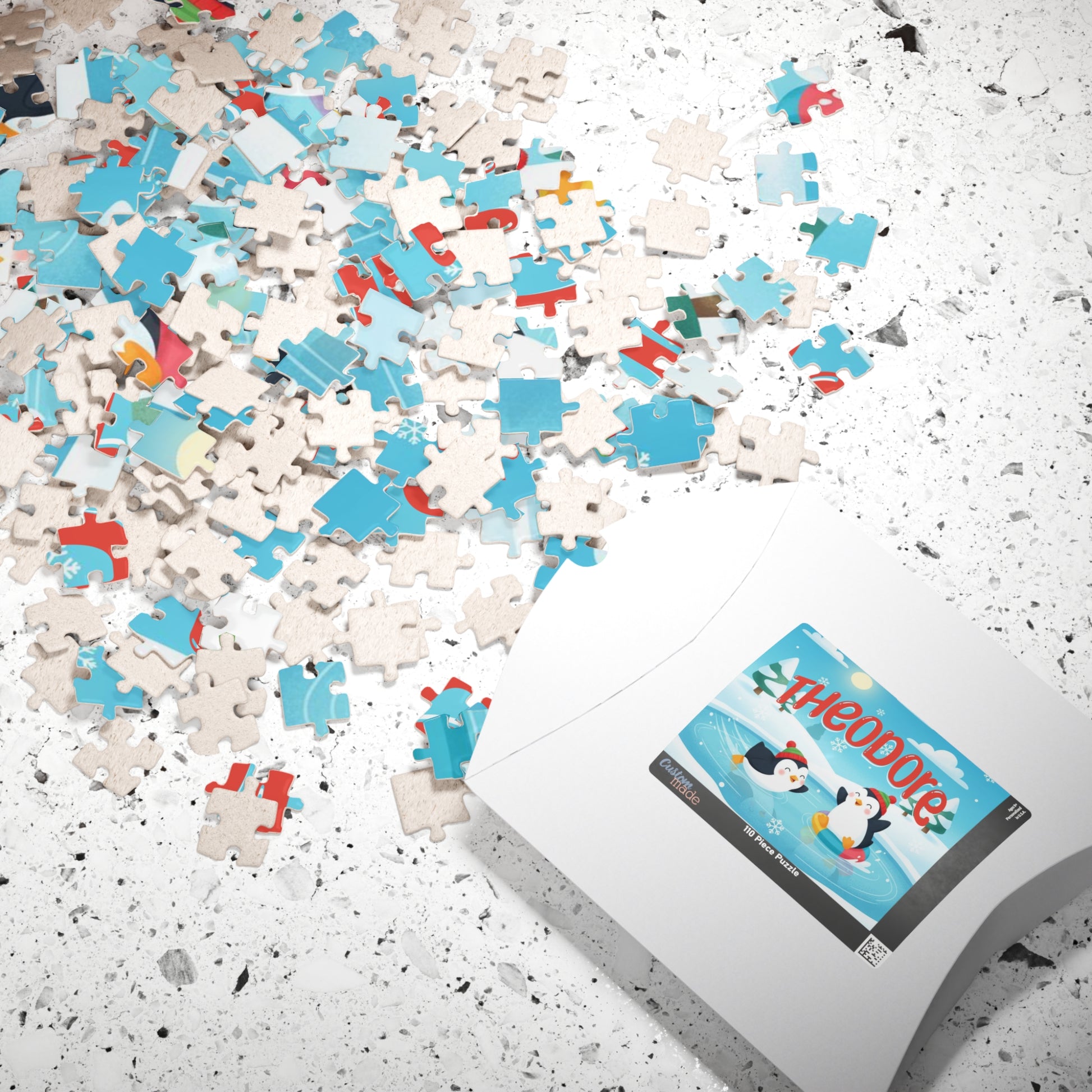 Personalized Christmas puzzle pieces scattered beside the puzzle box featuring a custom name and cheerful penguin winter design.
