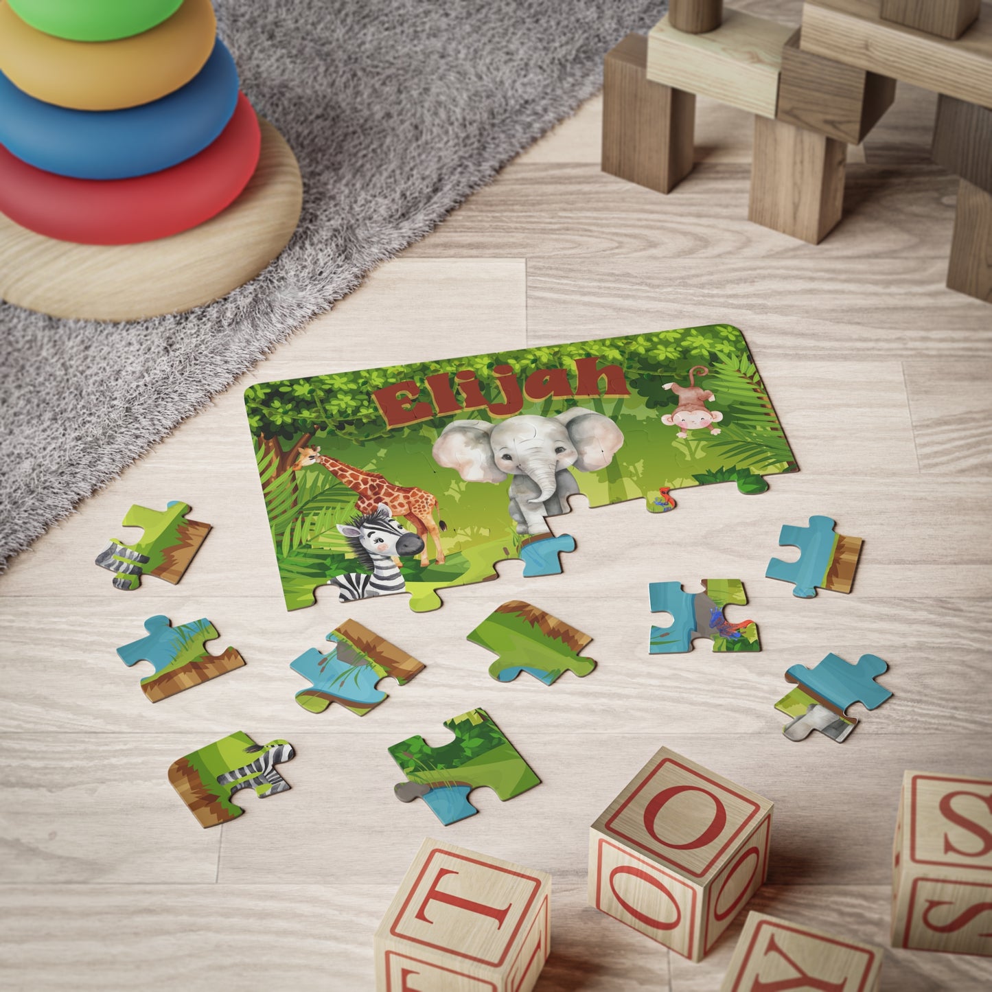 Personalized 30-piece jungle animal jigsaw puzzle shown partially assembled on the floor, with the child’s custom name displayed across the top and individual jigsaw pieces scattered around.
