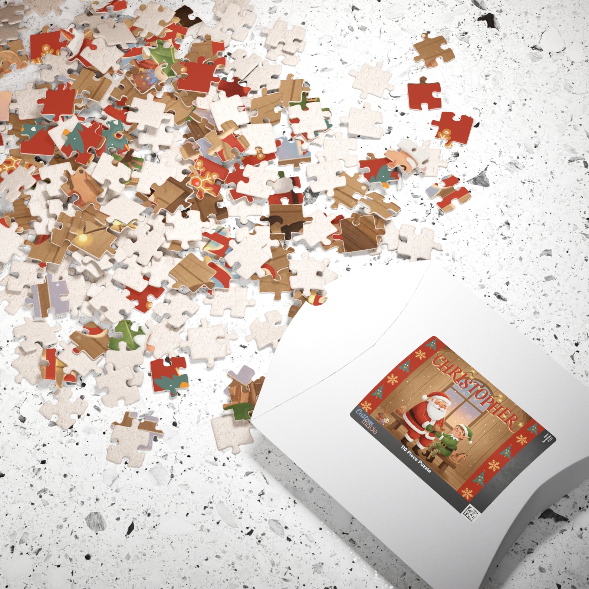 Scattered personalized Christmas puzzle pieces beside the puzzle box featuring a custom Santa and elf holiday workshop design.