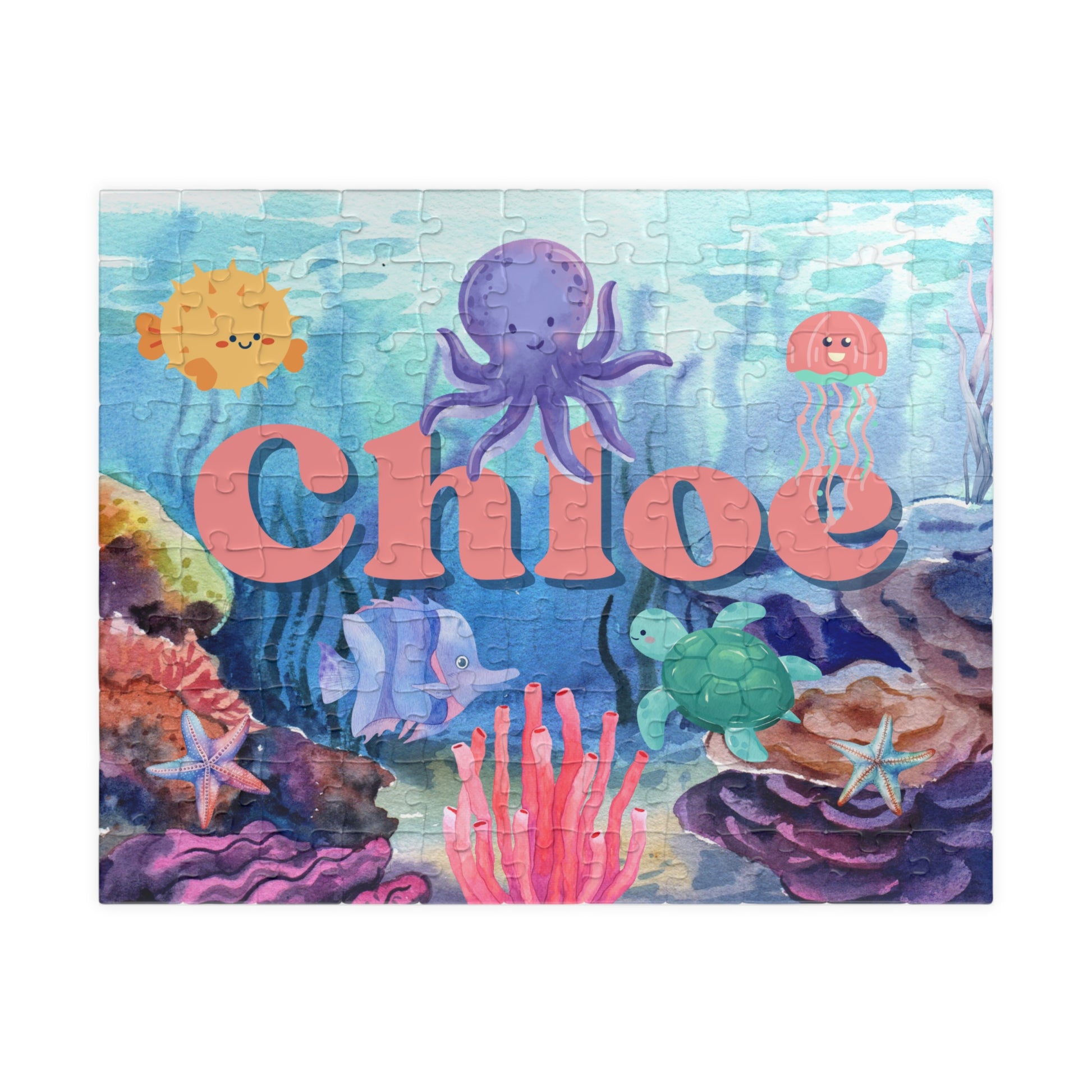 Personalized ocean-themed 110-piece jigsaw puzzle featuring a colorful underwater scene with sea animals, coral, and fish. A customizable child’s name appears prominently across the center of the puzzle design.