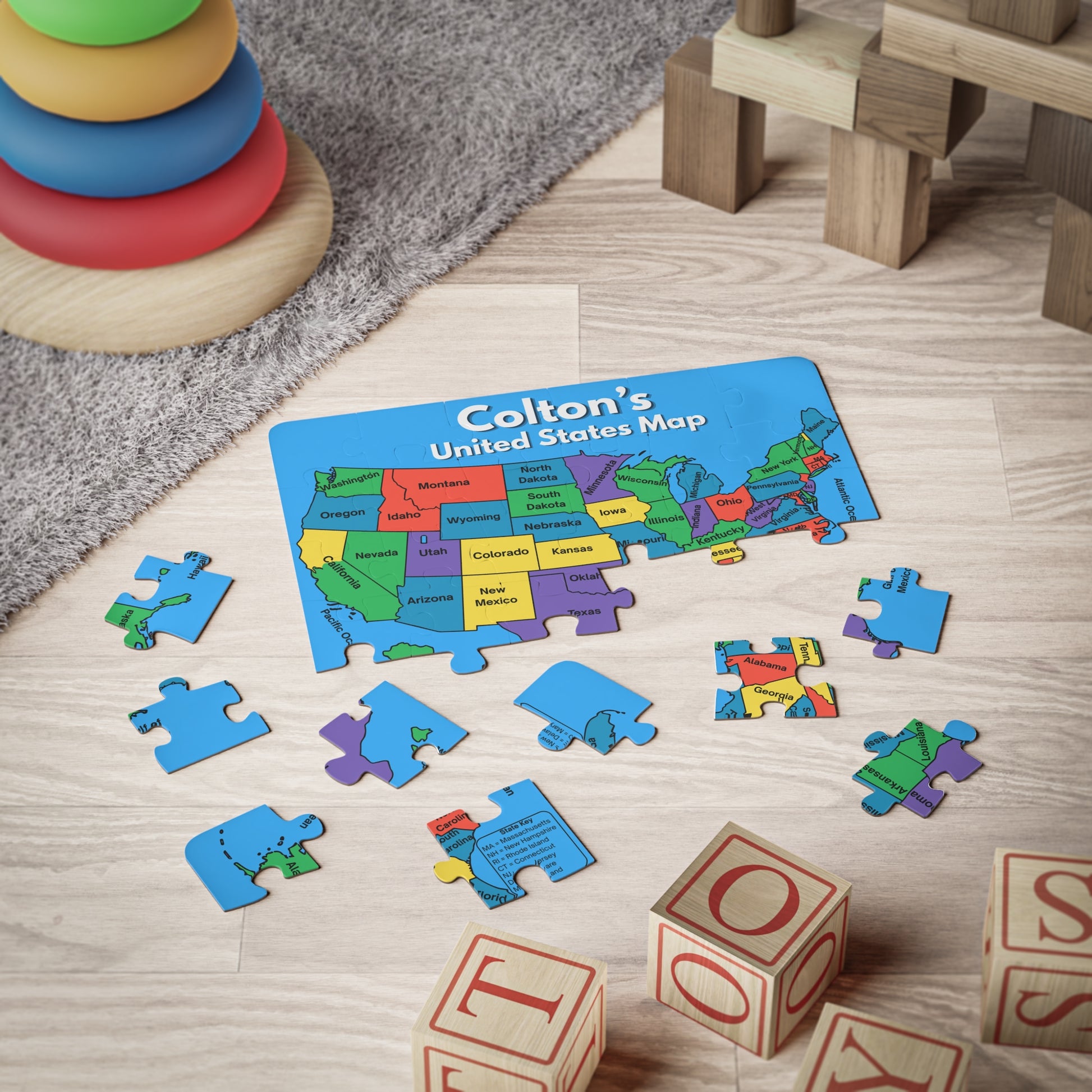 Personalized United States map puzzle partially assembled on a playroom floor, showing large puzzle pieces designed for small hands and geography learning.