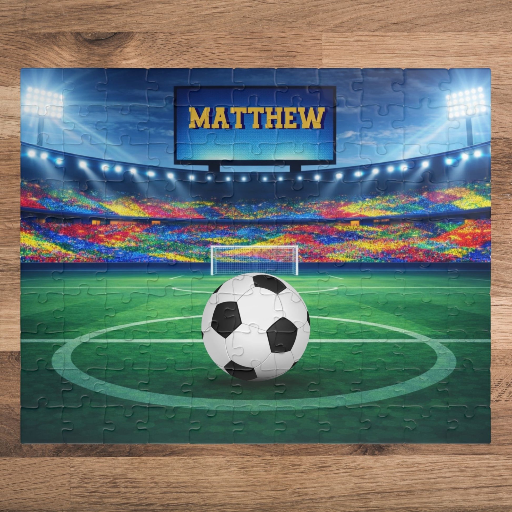Fully assembled personalized soccer stadium jigsaw puzzle. Customizable name is displayed on the stadium screen above the field. 110-piece puzzle design. 