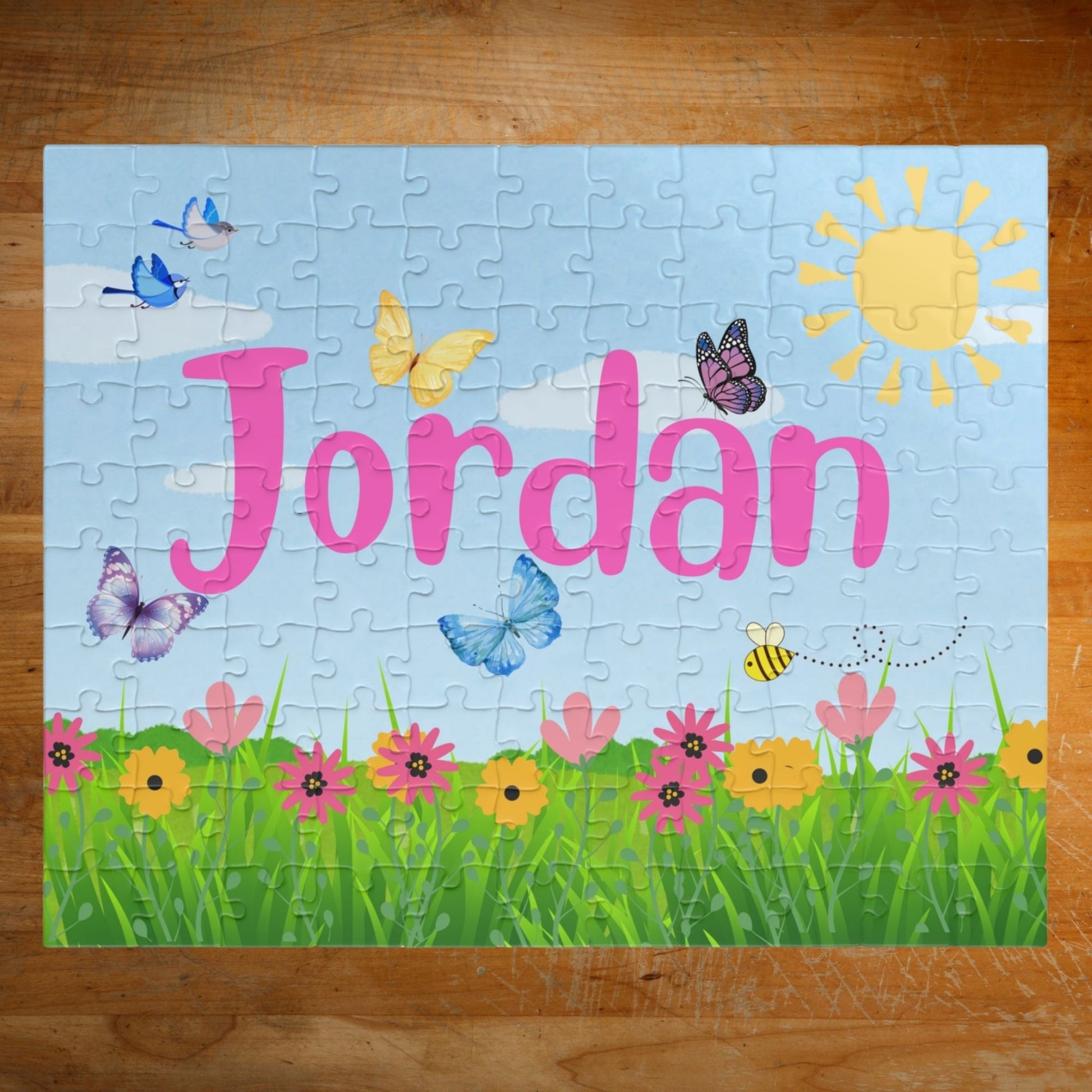 Personalized 110 piece spring themed jigsaw puzzle with a customizable name displayed across the center, featuring butterflies, birds, flowers, green grass, and a sunny sky