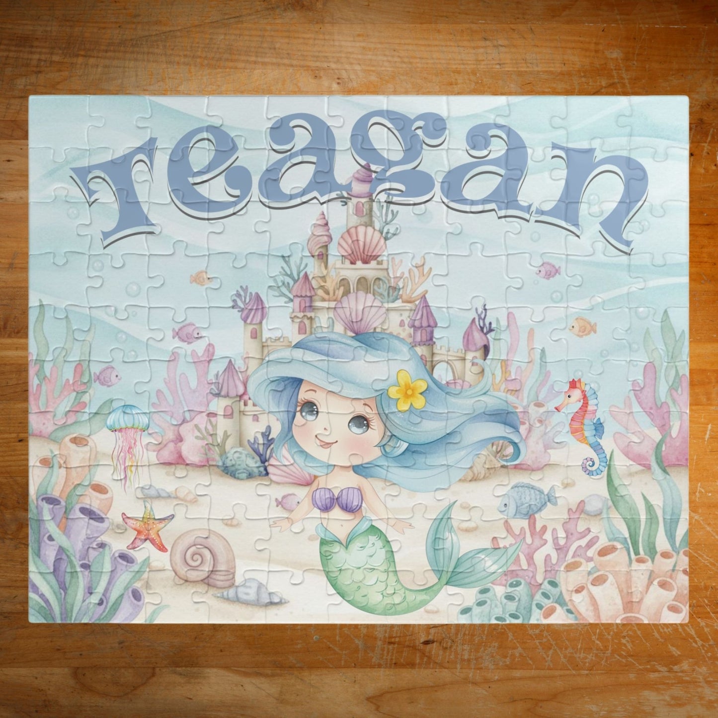 Completed personalized mermaid puzzle featuring an underwater ocean scene with a mermaid, coral, seashells, seahorse, fish, castle, and a customizable child’s name displayed prominently at the top.
