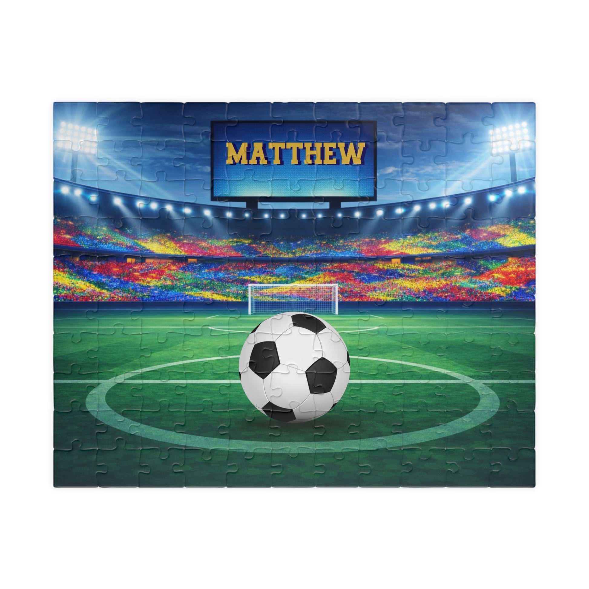 Fully assembled personalized soccer stadium jigsaw puzzle with a close-up inset showing individual jigsaw pieces. Customizable name is displayed on the stadium screen above the field. 110-piece puzzle design.
