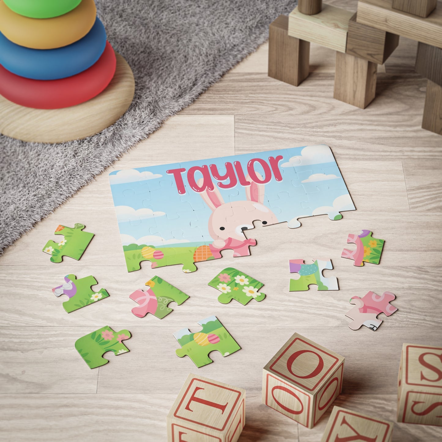 Personalized Easter bunny jigsaw puzzle shown partially assembled on the floor, with colorful jigsaw pieces scattered around and a customizable name printed across the top of the puzzle design.