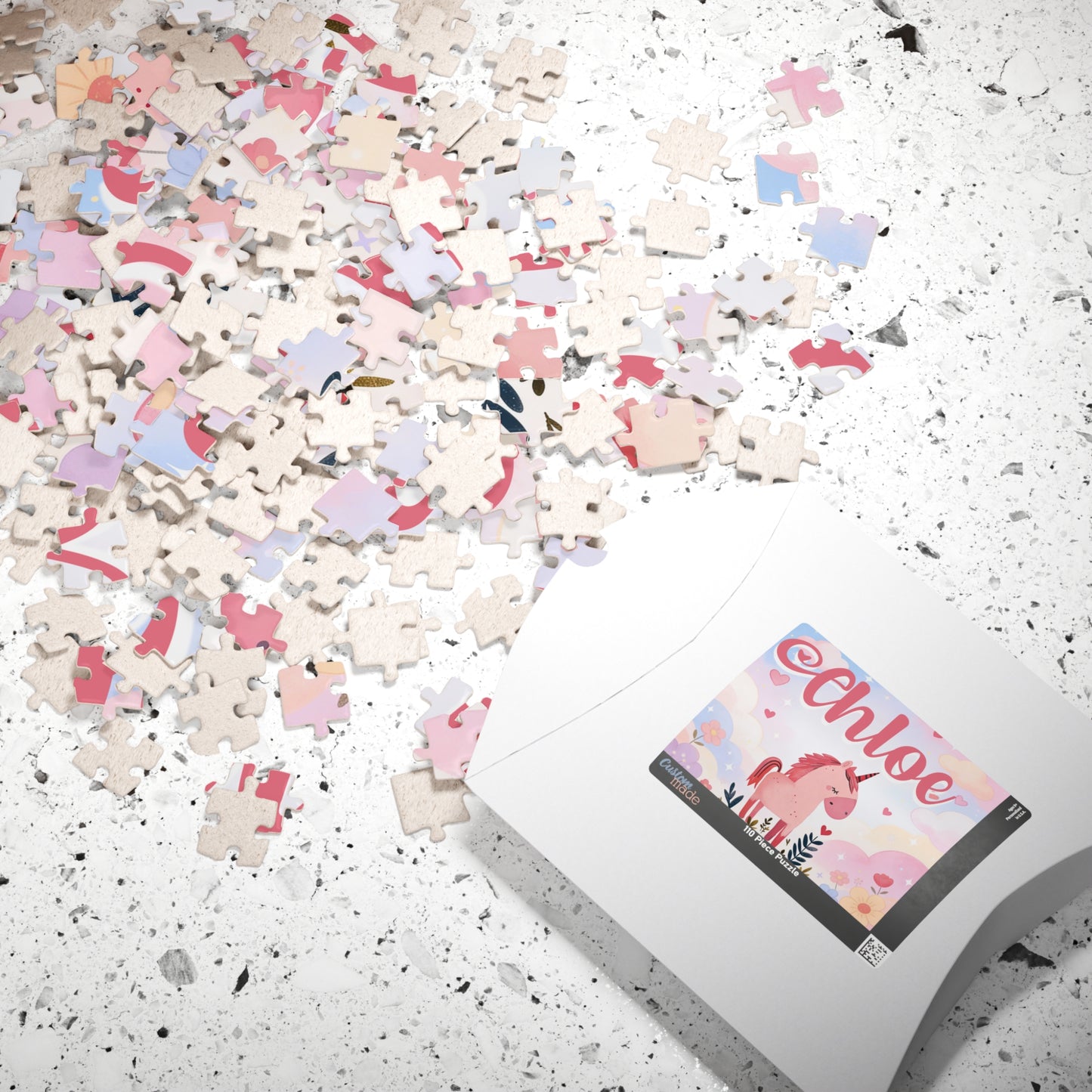Close-up of unicorn jigsaw puzzle pieces with pastel heart design and personalized name shown on box label