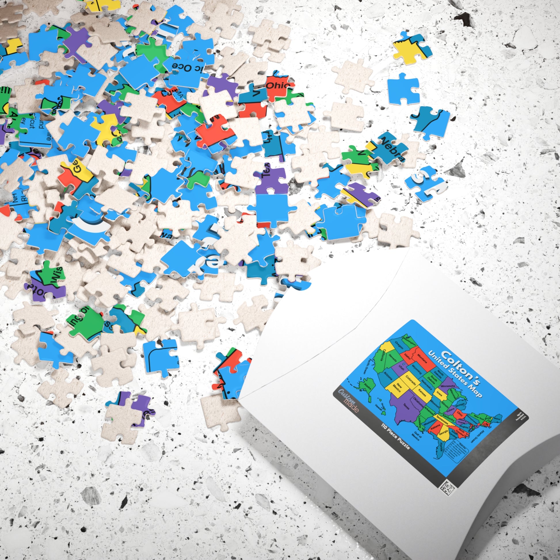 Personalized United States map puzzle pieces scattered beside the included storage box featuring the custom name educational USA map design.