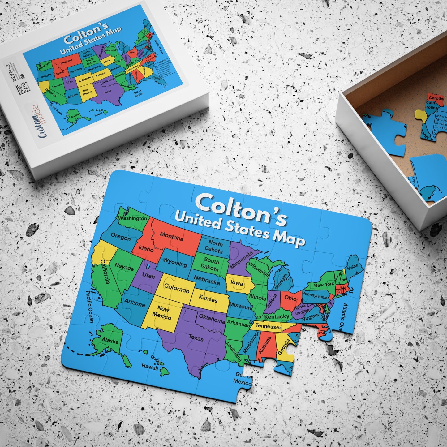 Personalized 30-piece United States map puzzle displayed beside its storage box with one piece removed, featuring a colorful labeled map of all 50 states.