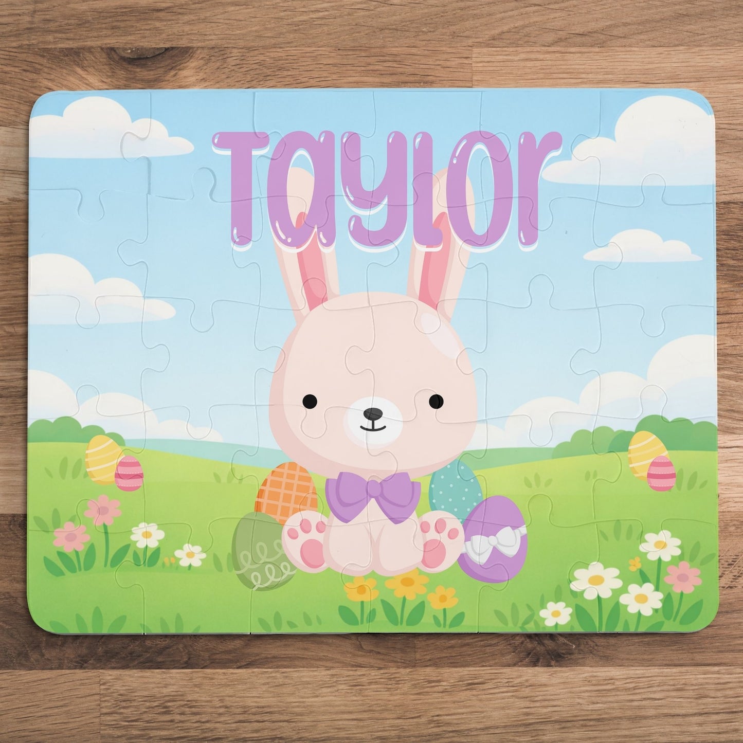 Fully assembled personalized Easter bunny jigsaw puzzle featuring a cheerful bunny in a spring meadow scene, with a customizable name printed across the top of the puzzle.