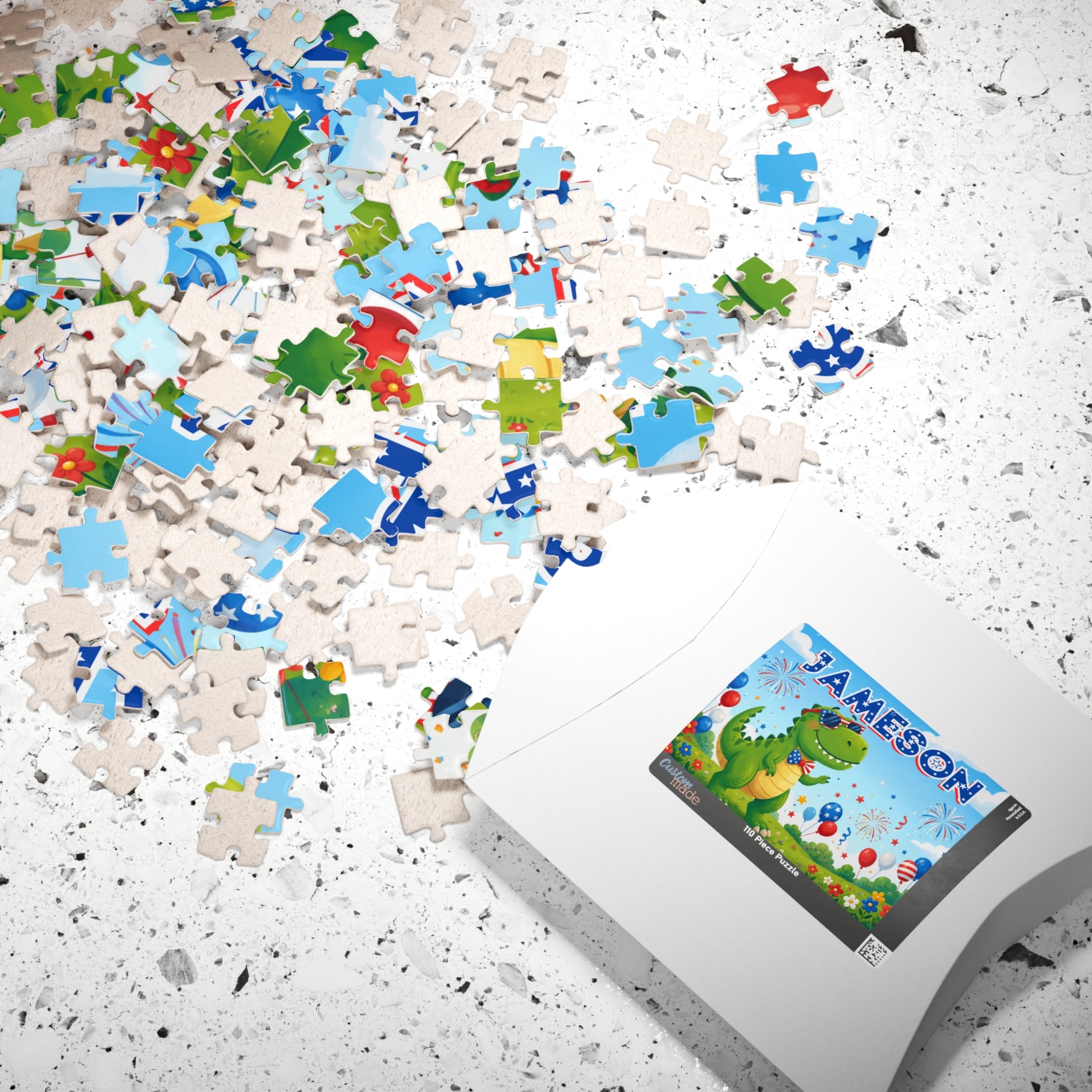 Scattered puzzle pieces and packaging displaying a personalized dinosaur puzzle with custom name, patriotic colors, fireworks, and festive 4th of July design.