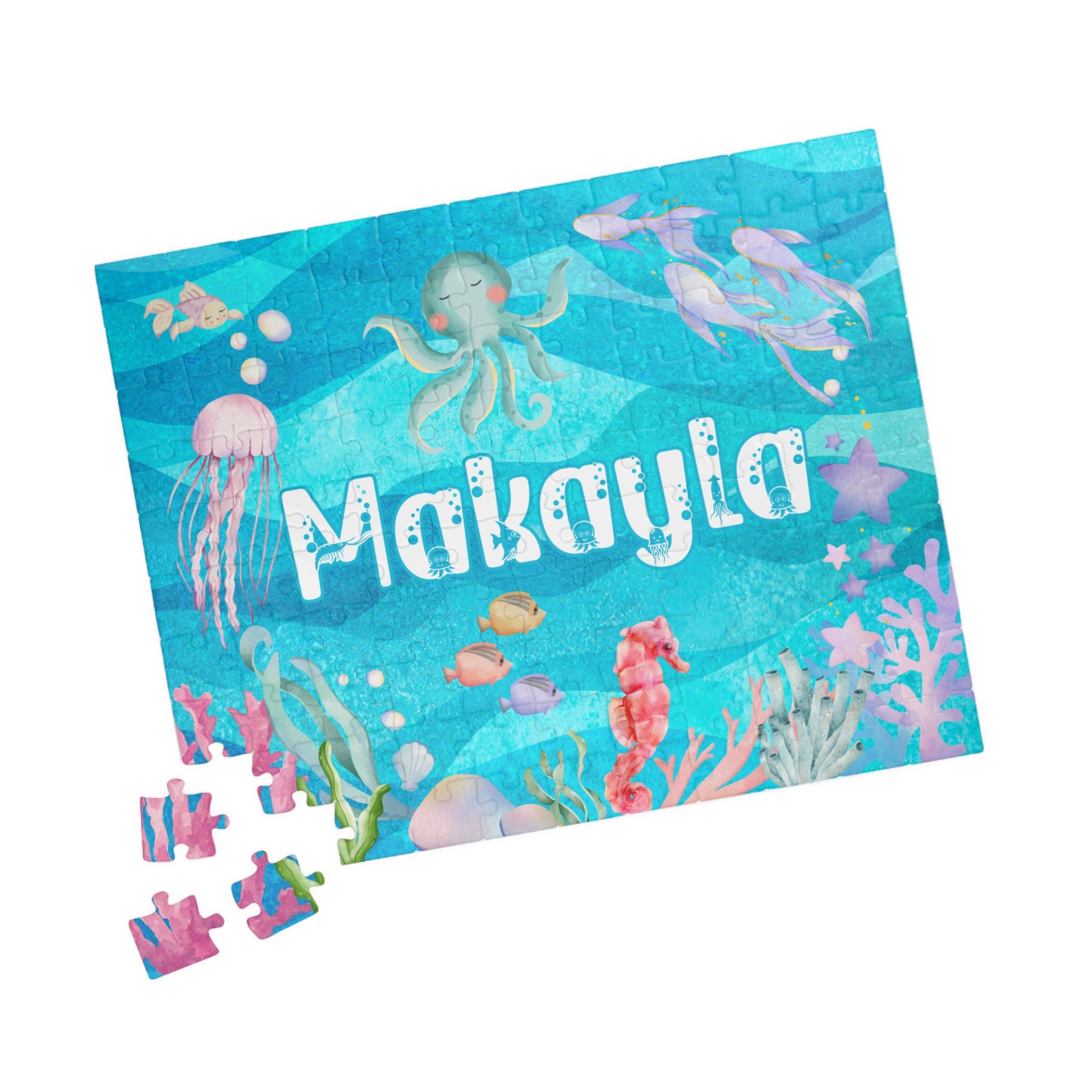 Scattered 110 piece ocean themed jigsaw puzzle pieces showing colorful underwater artwork and sea life, personalized puzzle with custom name option