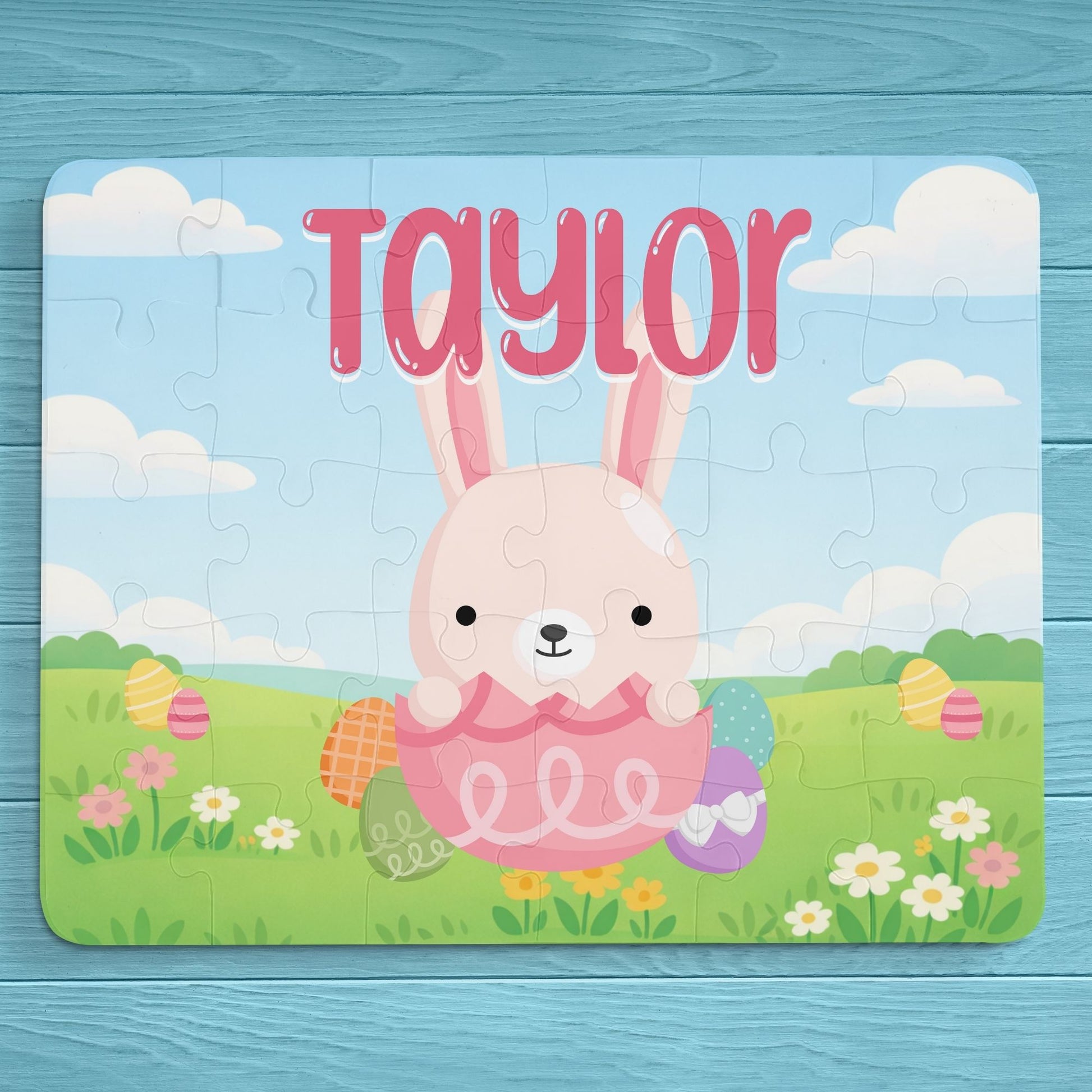 Fully assembled personalized Easter bunny jigsaw puzzle featuring a cheerful bunny sitting in a decorated egg within a spring meadow scene, with a customizable name printed across the top of the puzzle.