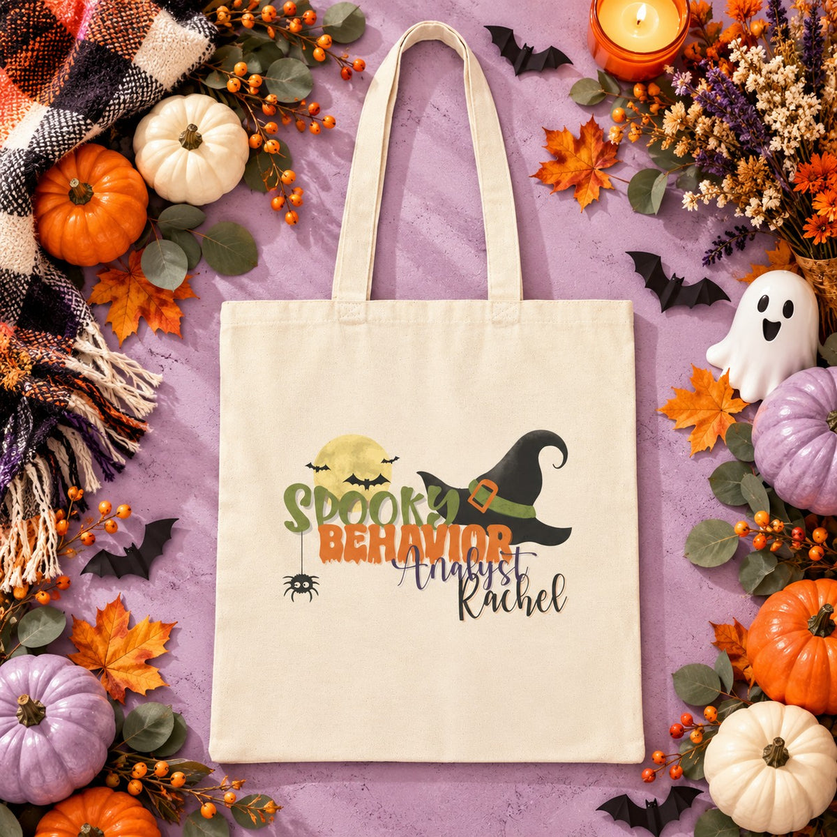 Personalized cotton canvas tote bag in a Halloween-themed lifestyle scene, featuring a spooky design with a witch hat and moon, and a customizable name printed beneath the main design on the front of the bag. for behavior analyst